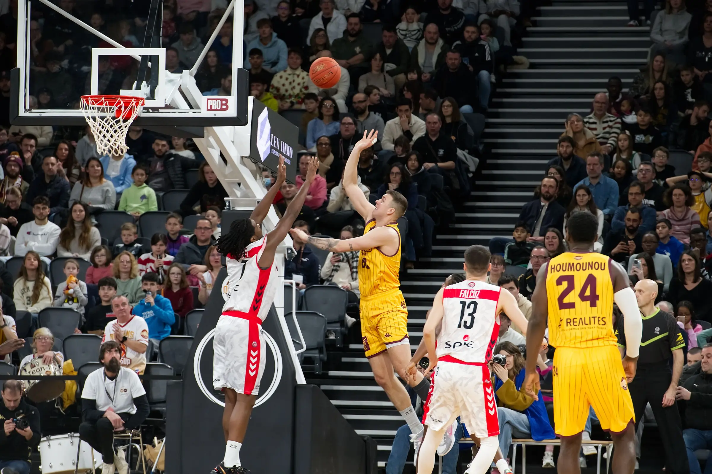 Jugador de baloncesto lanzando a canasta con un defensor saltando al tiro
