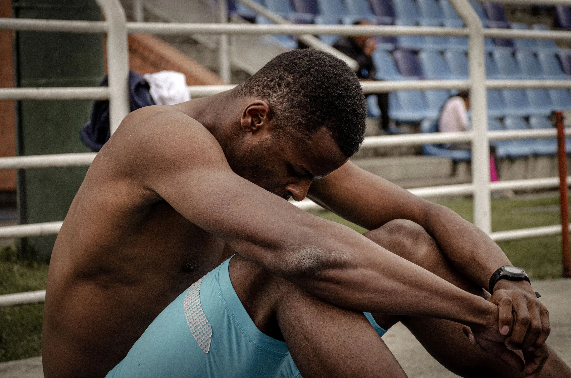 Deportista sentado y agotado en las gradas al terminar de entrenar