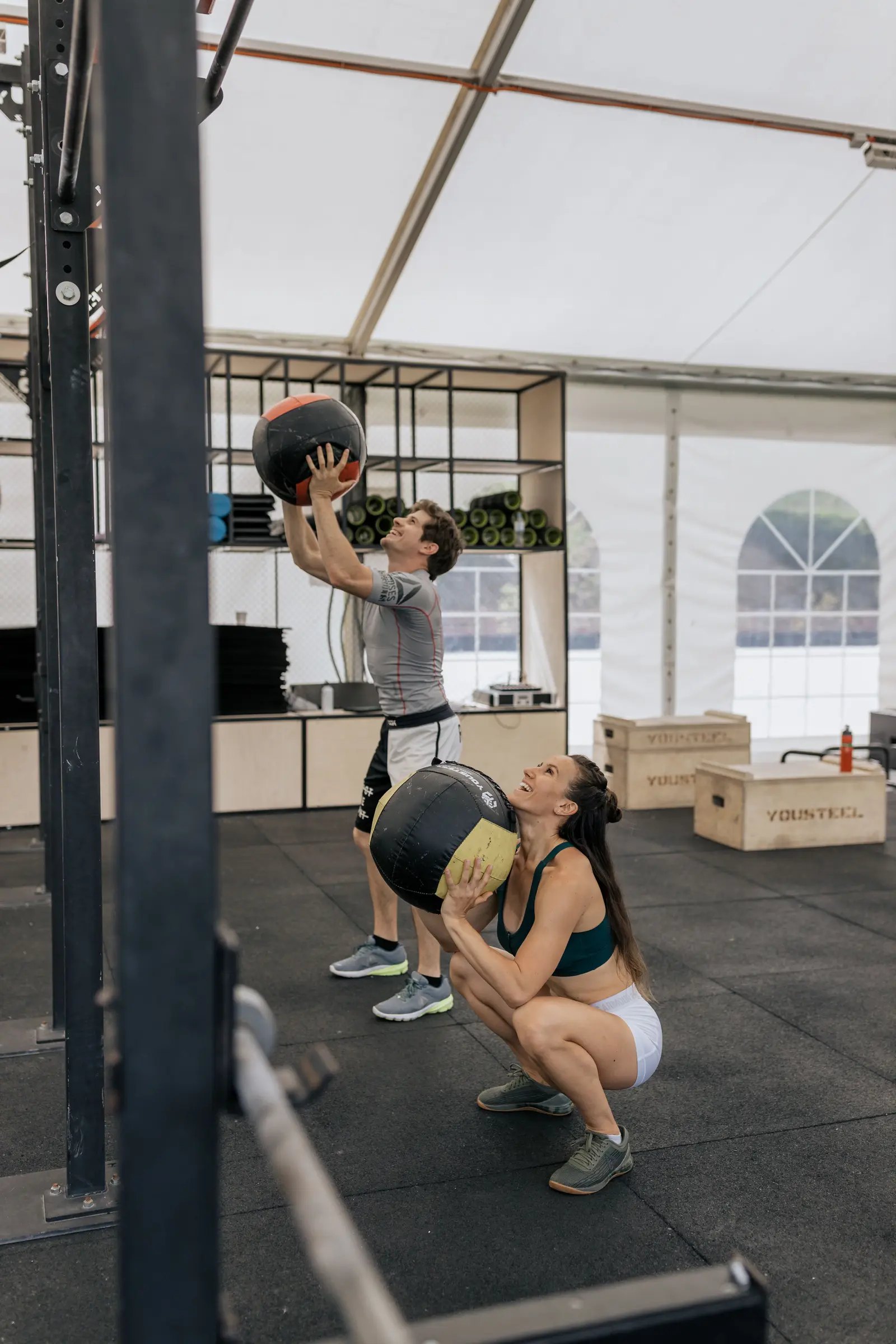 Dos personas entrenando con balón medicinal en una sala de acondicionamiento